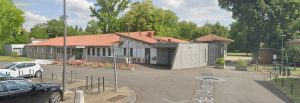 Vue arrière de l'auberge côté parking et chemin menant au parc